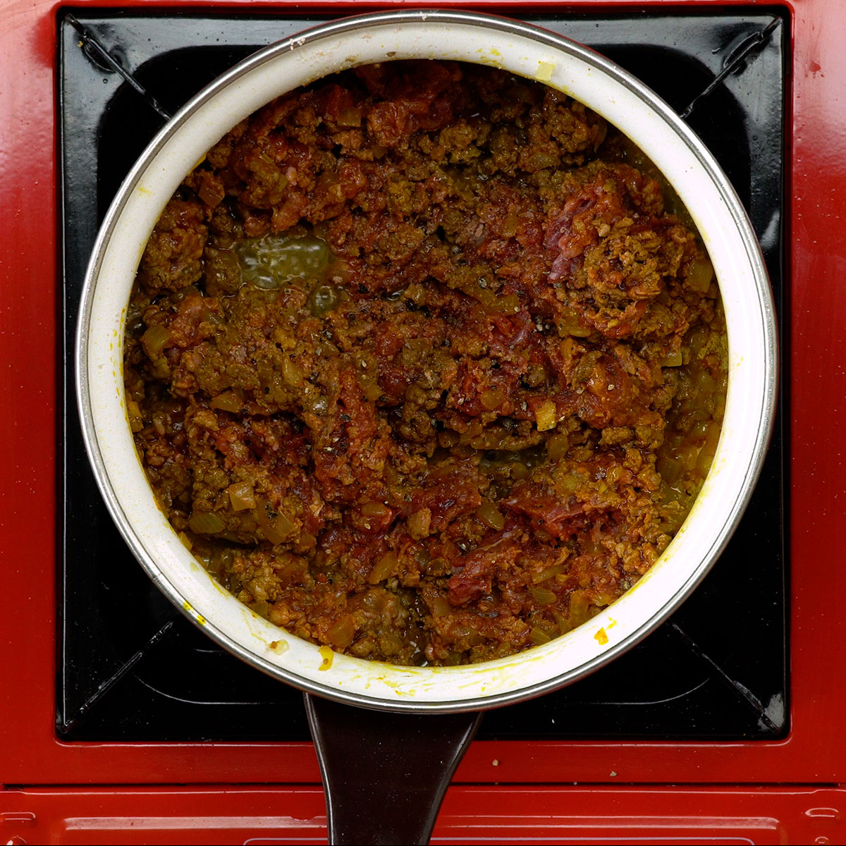 Carne moída sendo temperada com sal e pimenta-do-reino.
