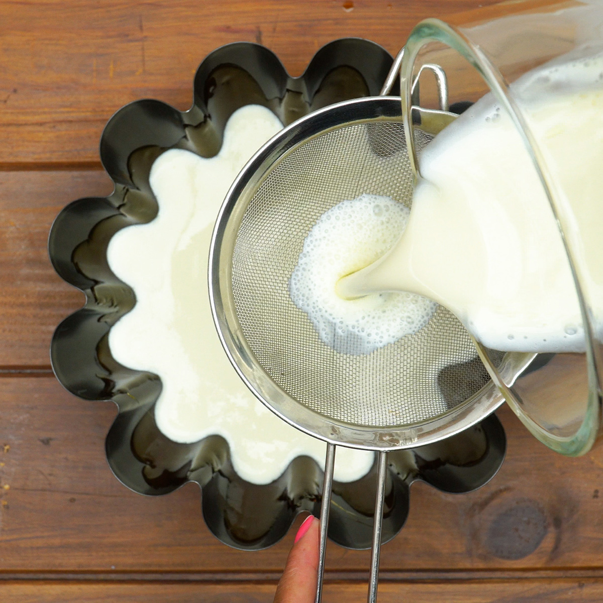 Mistura do pudim sendo coada diretamente na forma caramelizada.