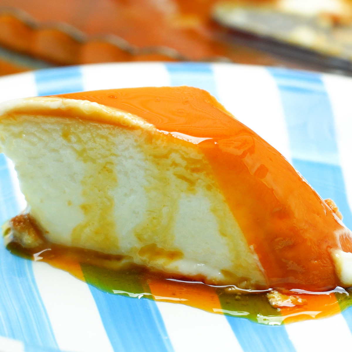 Pudim de iogurte desenformado com calda de caramelo escorrendo, servido em fatia.