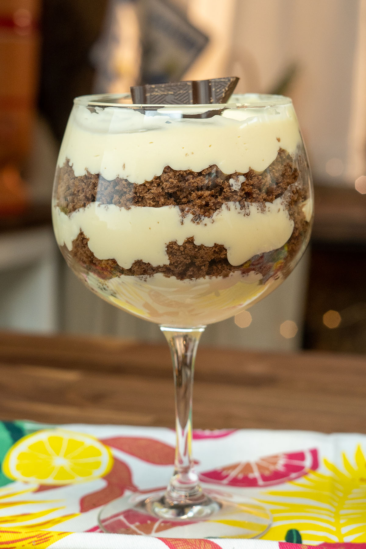 Taça de mousse de maracujá com camada de bolo e pedaços de chocolate decorativos.