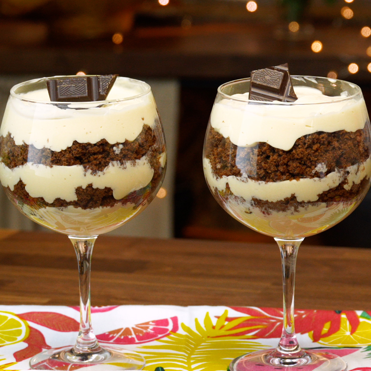 Taça de mousse de maracujá com camada de bolo e pedaços de chocolate decorativos.