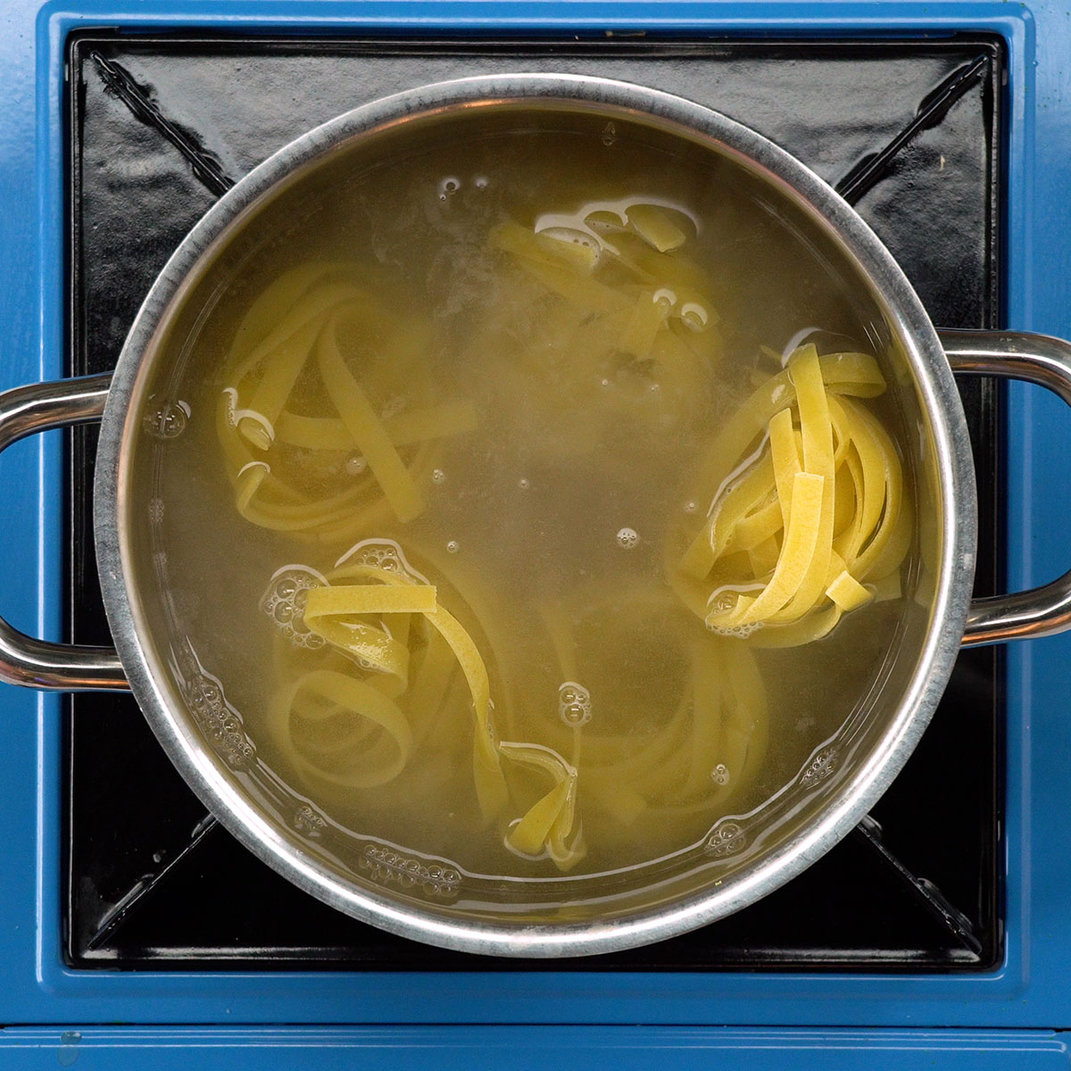 Tagliatelle cozinhando em panela com água fervente.