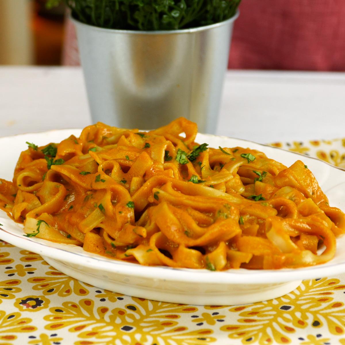 Tagliatelle com molho cremoso de camarão finalizado com salsa e servido no prato.