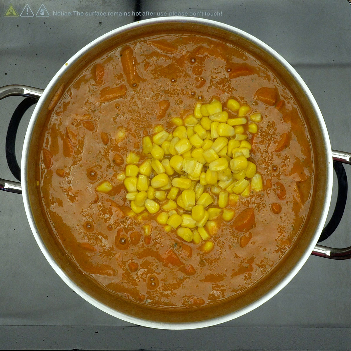 Salsichas em rodelas cozinhando no molho com milho.