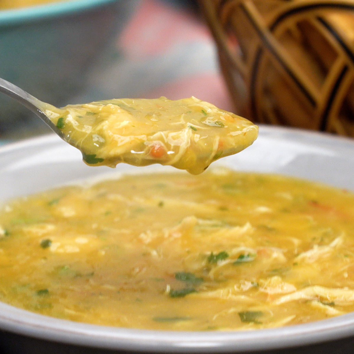 Caldo de frango com mandioca finalizado com coentro sendo servido.
