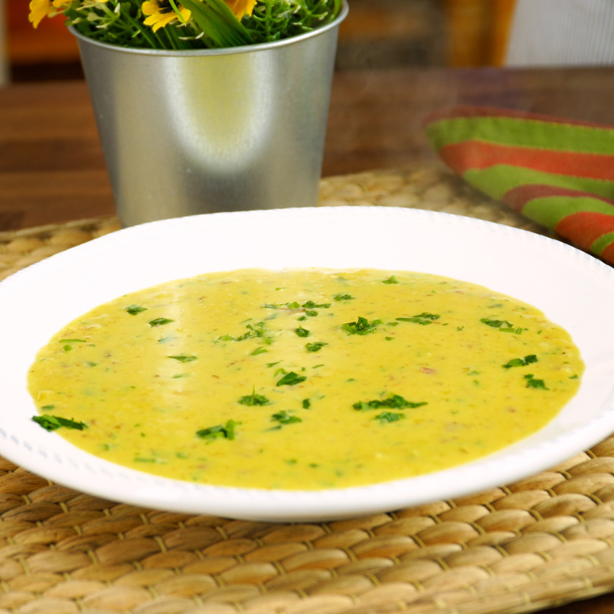 Creme de milho com bacon servido quente em tigela, finalizado com salsa fresca picada.