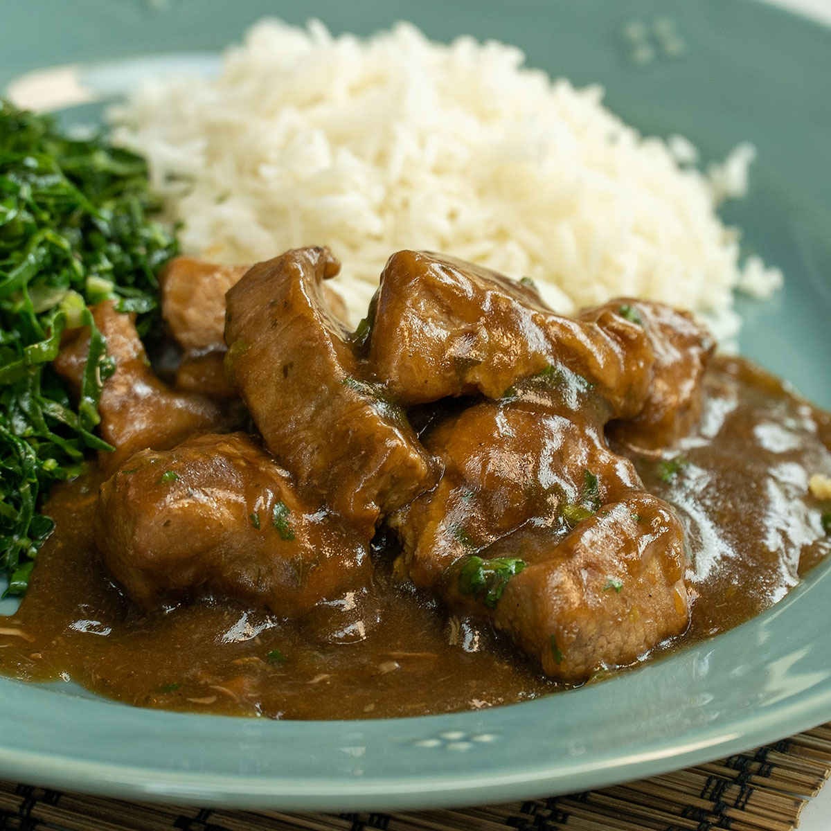 Empratamento de dadinho suíno na cerveja preta com arroz e couve de acompanhamento.