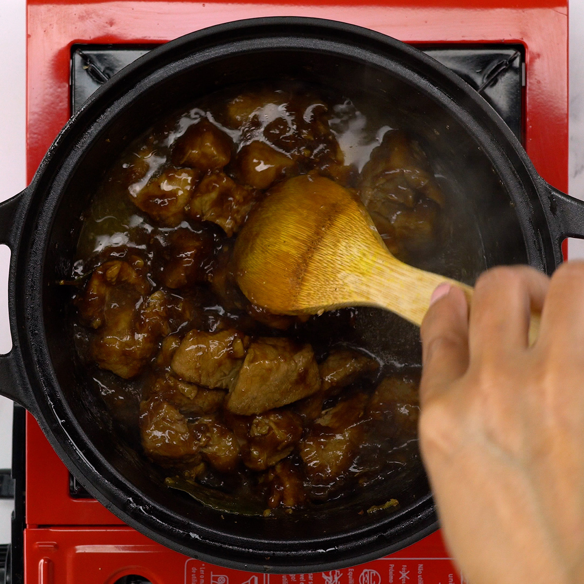 Molho engrossando e envolvendo os cubos de carne suína.