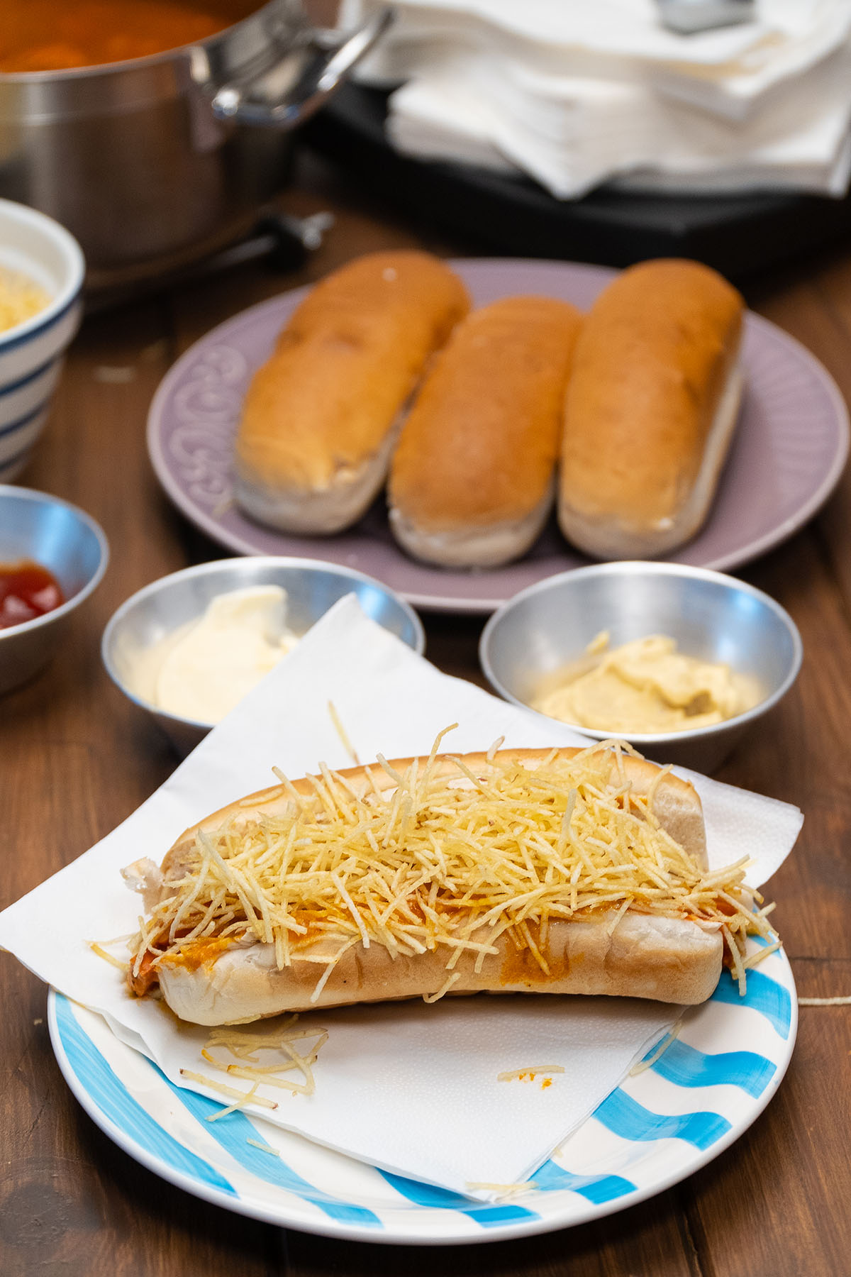 Cachorro-quente cremoso pronto servido com batata palha.