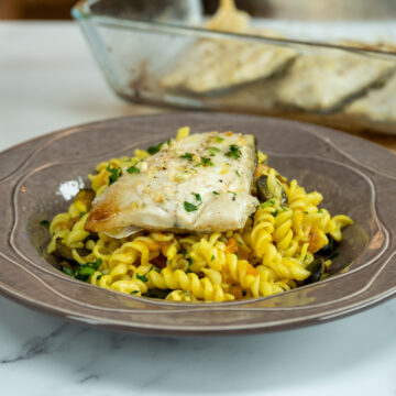 Empratamento filetes de robalo com macarrão espiral no forno servido.