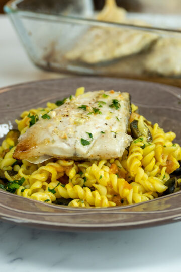 Empratamento filetes de robalo com macarrão espiral no forno servido.