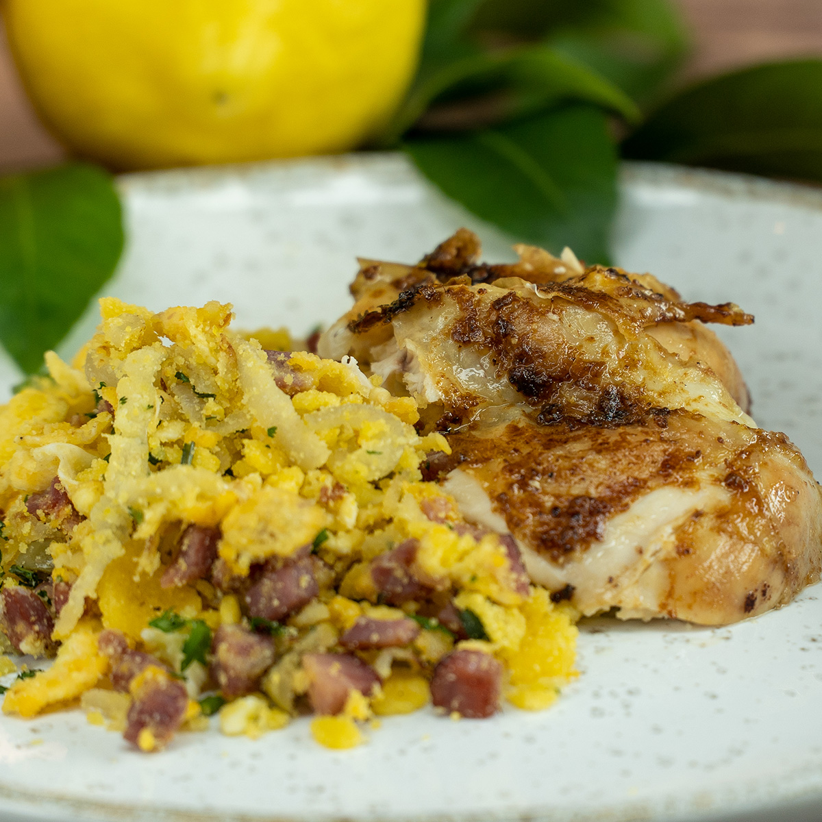 Empratamento de frango assado ao limão siciliano com farofa de acompanhamento.