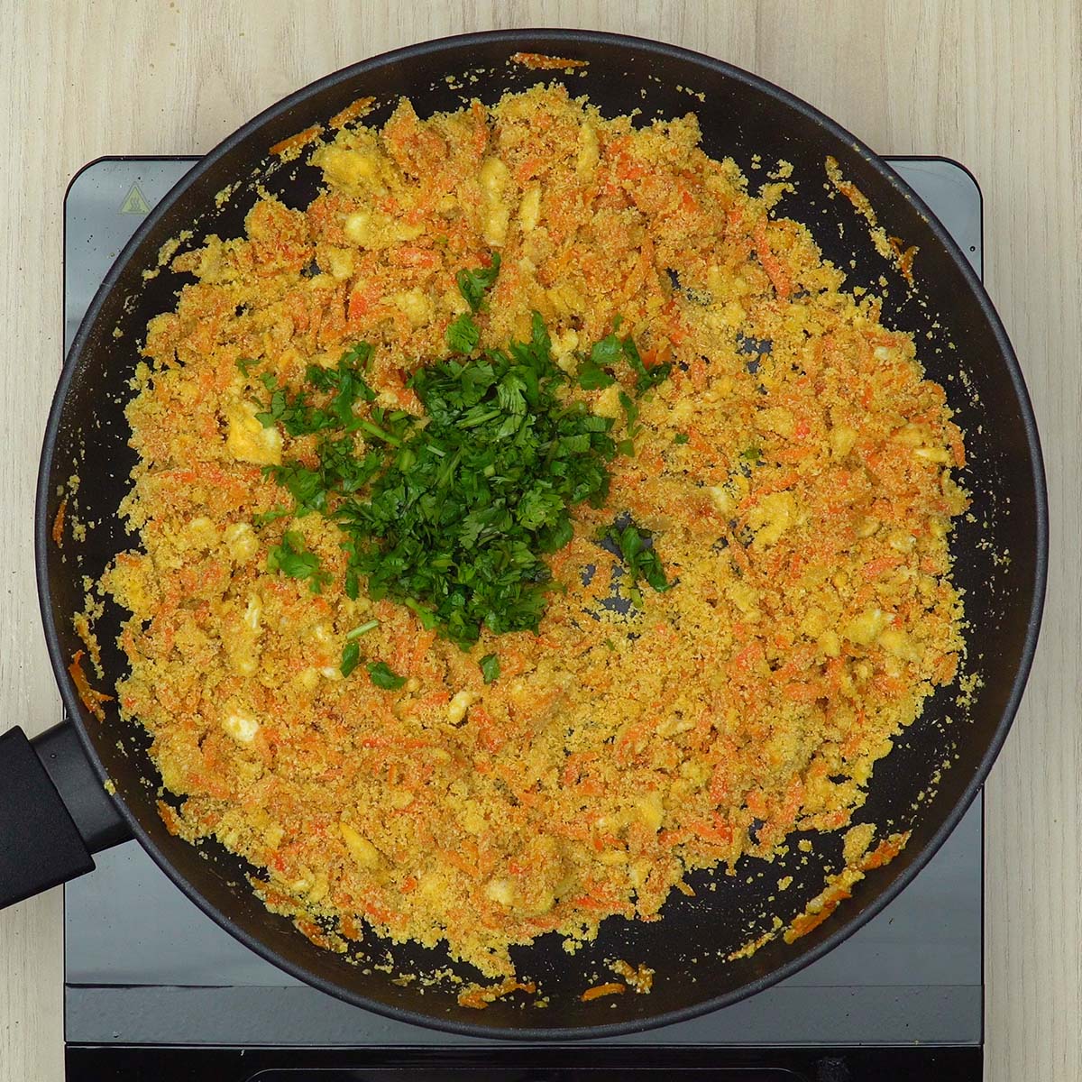 Farofa de cenoura com ovos finalizada com coentro picado.