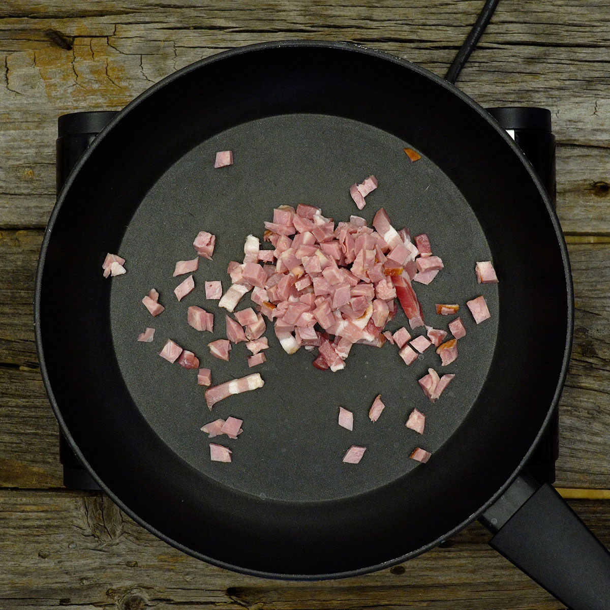 Bacon em cubos dourando na frigideira e liberando gordura para a farofa.