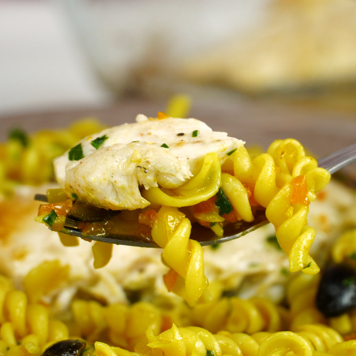 Prato de filetes de robalo com macarrão espiral sendo servido.