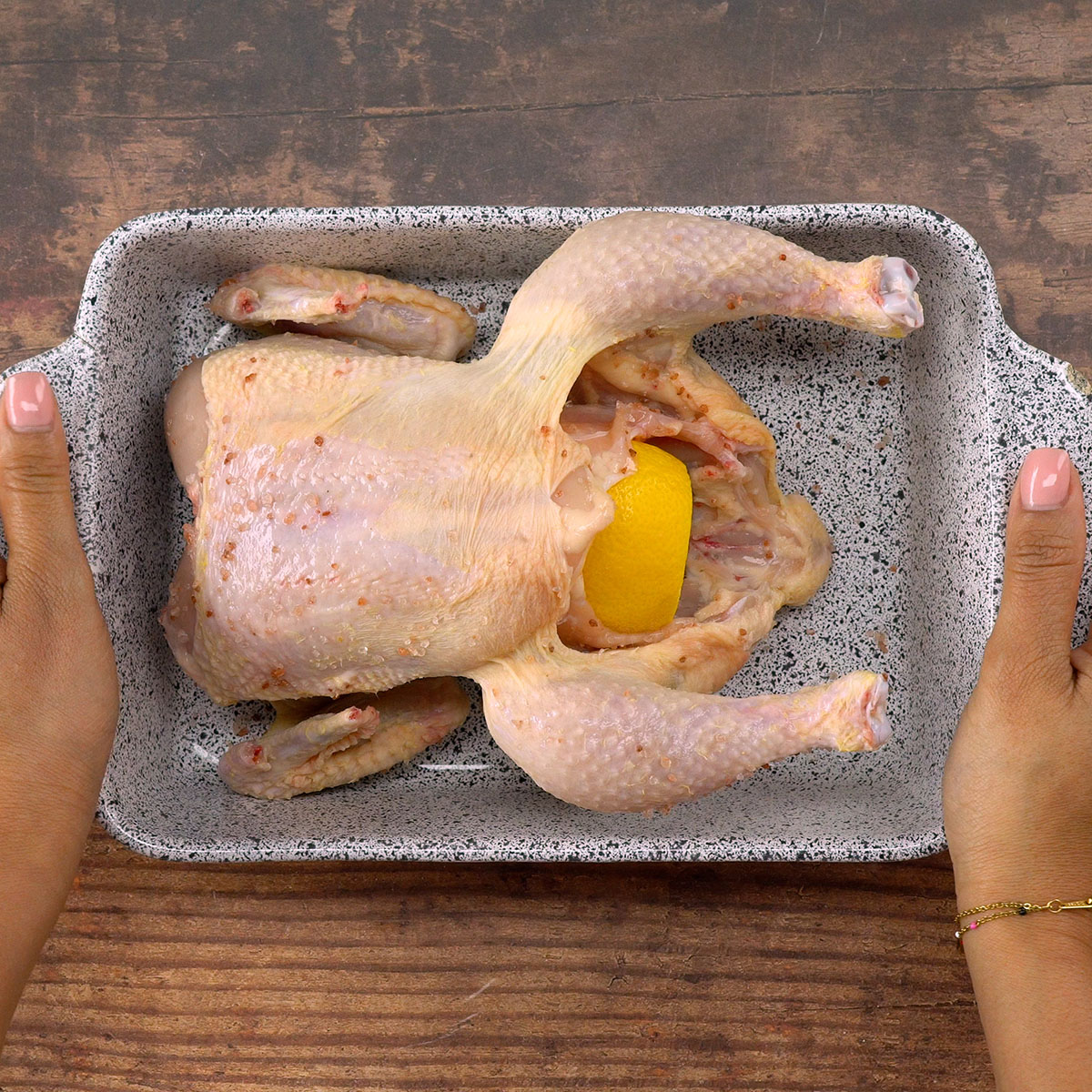 Frango assando no forno com o caldo sendo regado por cima.