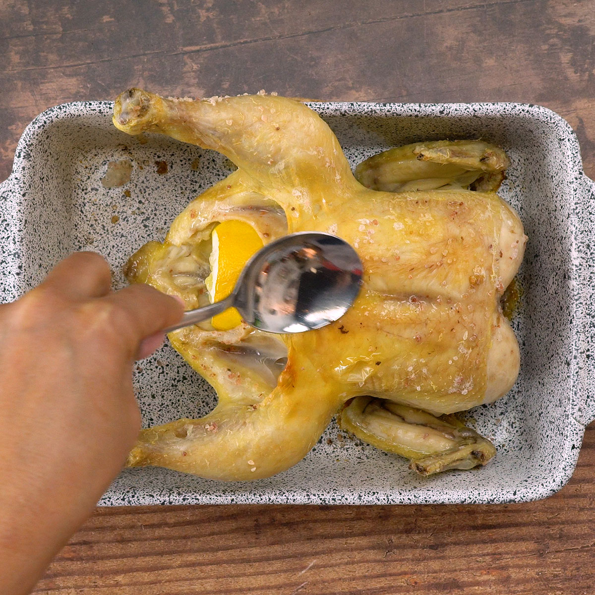 Frango assando no forno com o caldo sendo regado por cima.