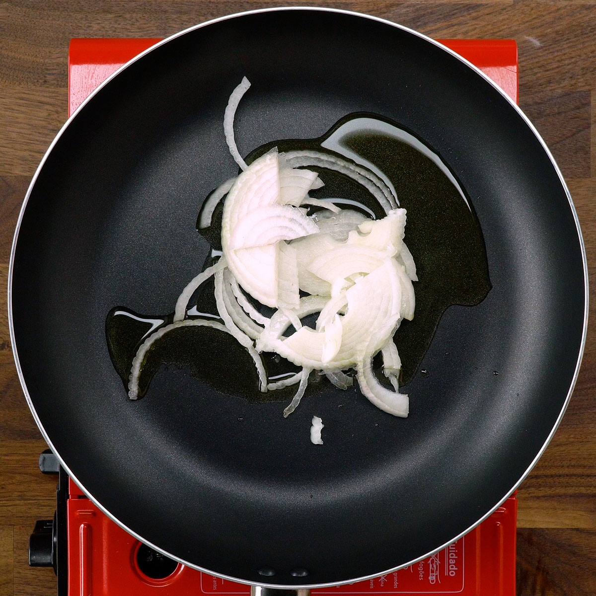 Cebola em meia-lua refogando no azeite até ficar macia.