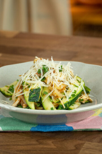 Empratamento frango com abobrinha finalizado com queijo parmesão ralado.