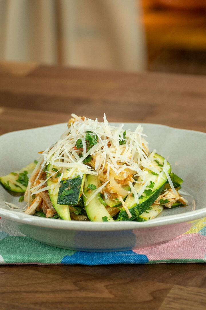 Empratamento frango com abobrinha finalizado com queijo parmesão ralado.
