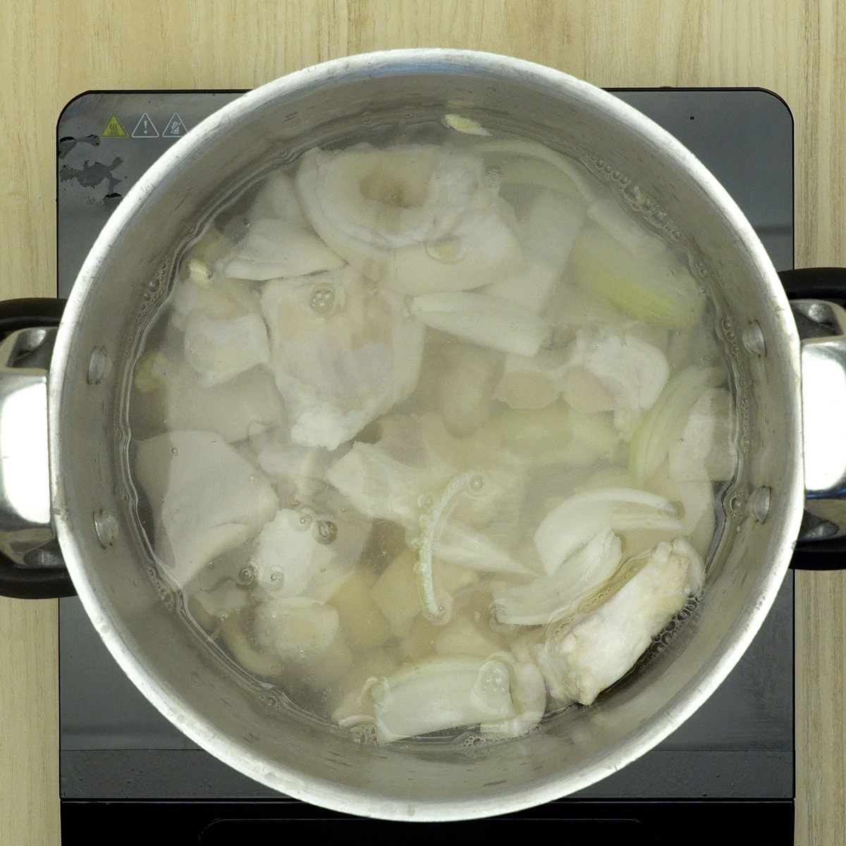 Mão de vaca cozinhando na panela de pressão com temperos.