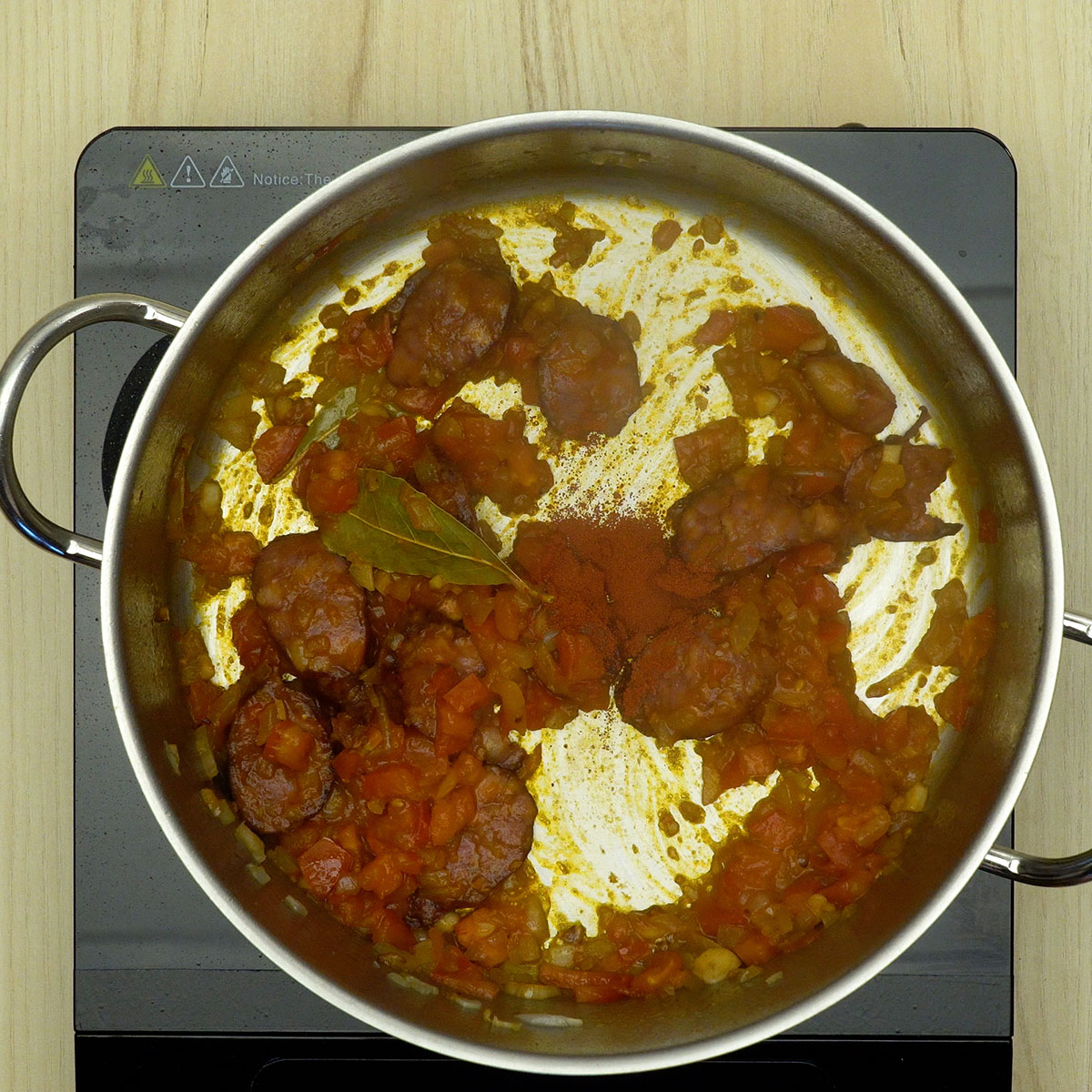 Molho com tomate, extrato e temperos sendo misturado na panela.