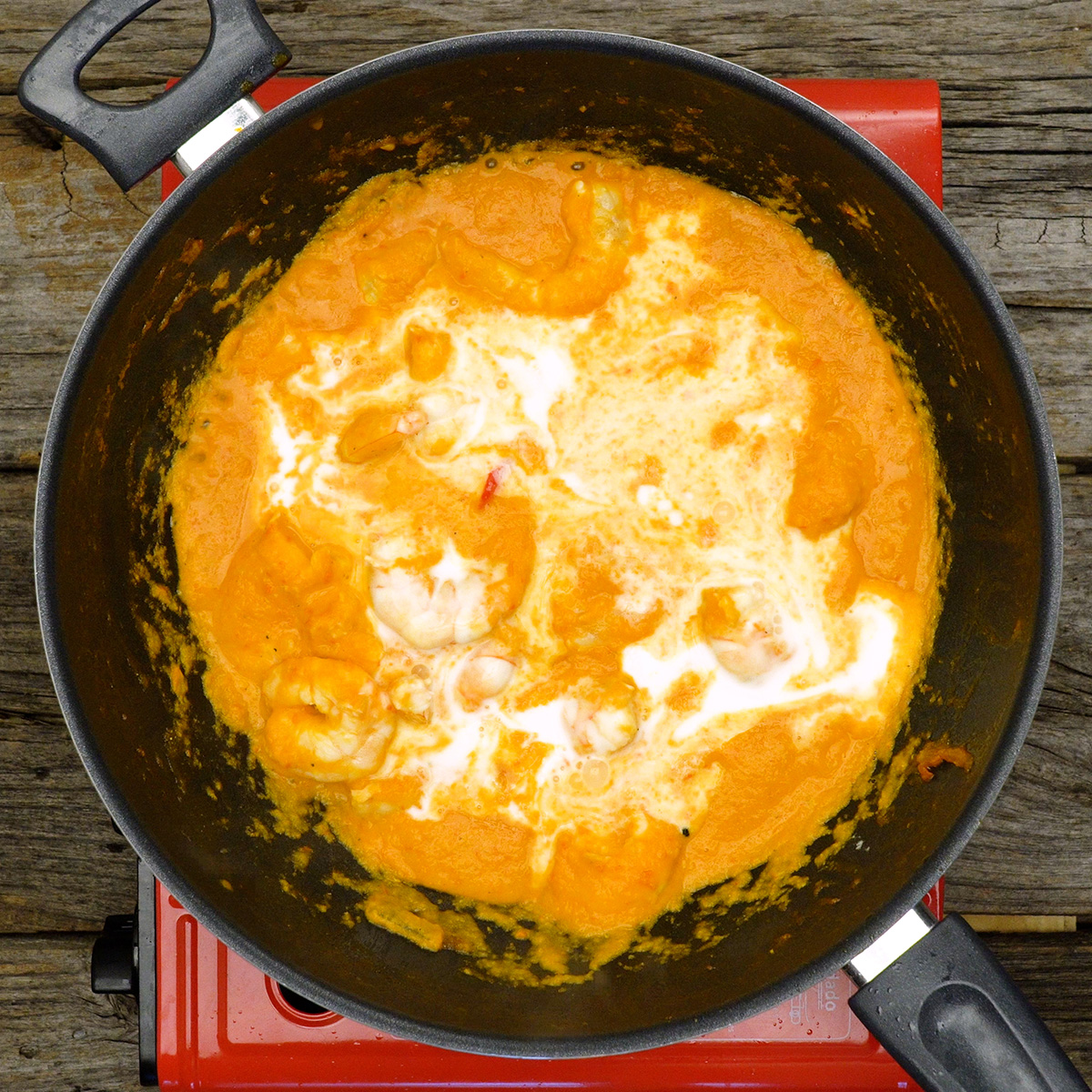 Moqueca de camarão cozinhando com leite de coco e molho cremoso.