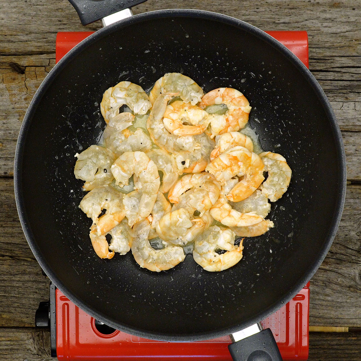 Camarão dourando levemente na frigideira com azeite.