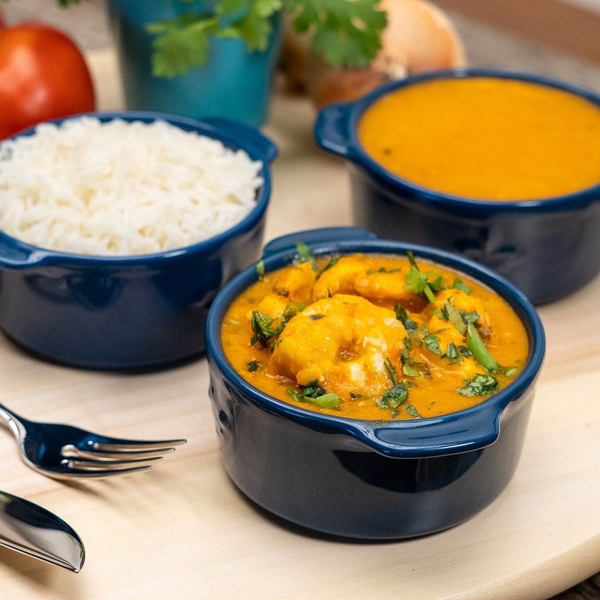 Moqueca de camarão finalizada com coentro e acompanhamentos.