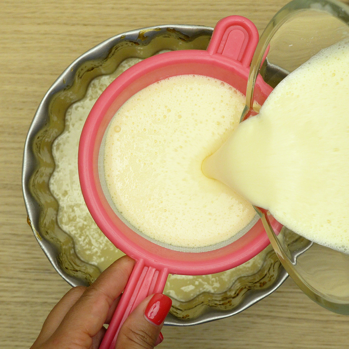 Creme de pudim dois leites sendo colocado suavemente na forma com caramelo.