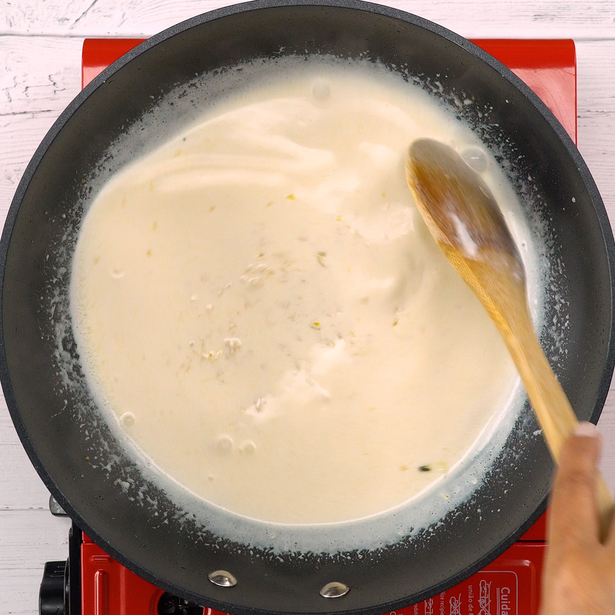 Molho cremoso com queijo parmesão e raspas de limão sendo preparado.