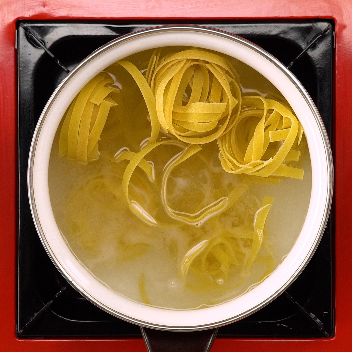 Tagliatelle cozinhando em panela com água fervente.