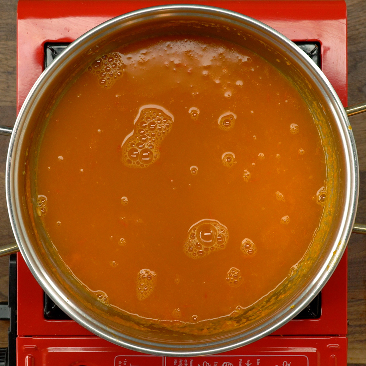Caldo de camarão sendo colocado no arroz durante o cozimento.