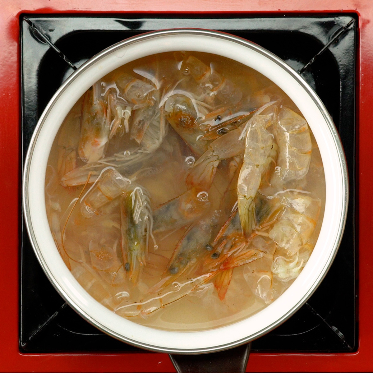 Caldo de camarão sendo preparado com cascas fervendo em panela.