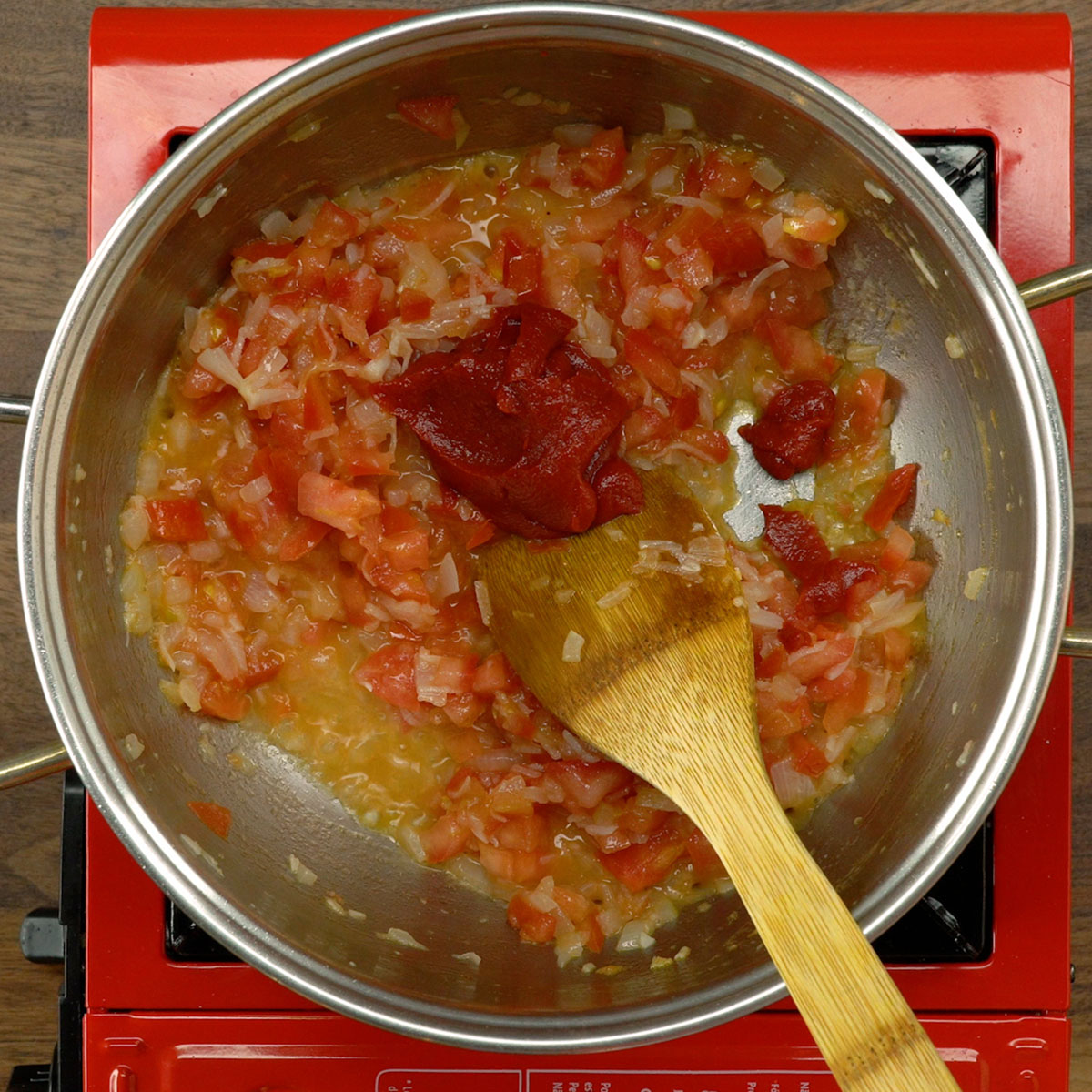 Extrato de tomate sendo misturado ao refogado cremoso do arroz de camarão.