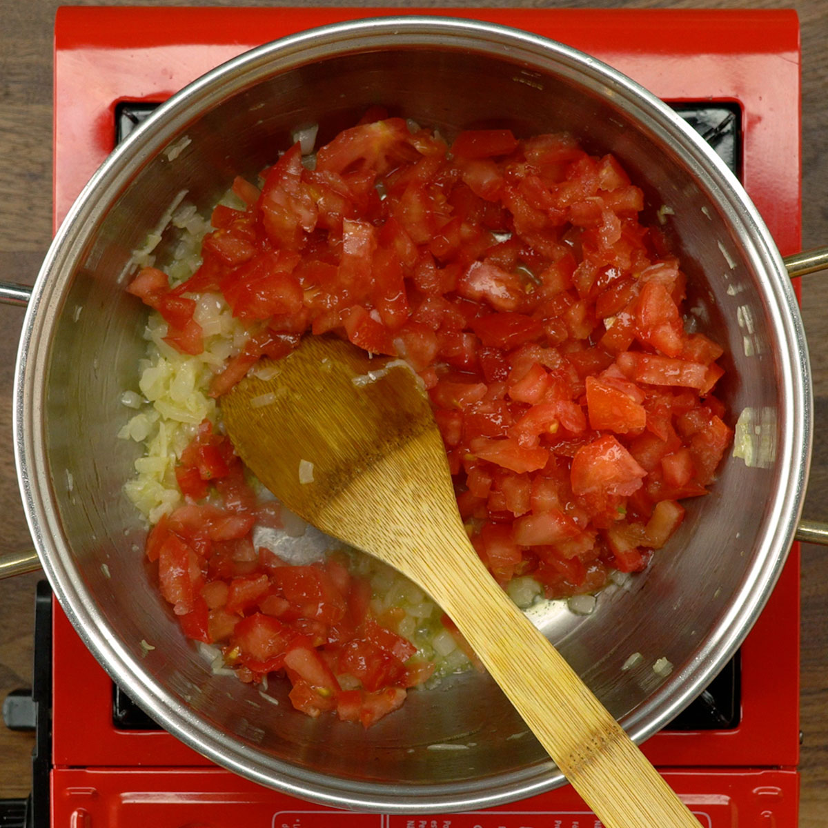 Cebola, alho e tomates refogando no azeite para arroz de camarão.