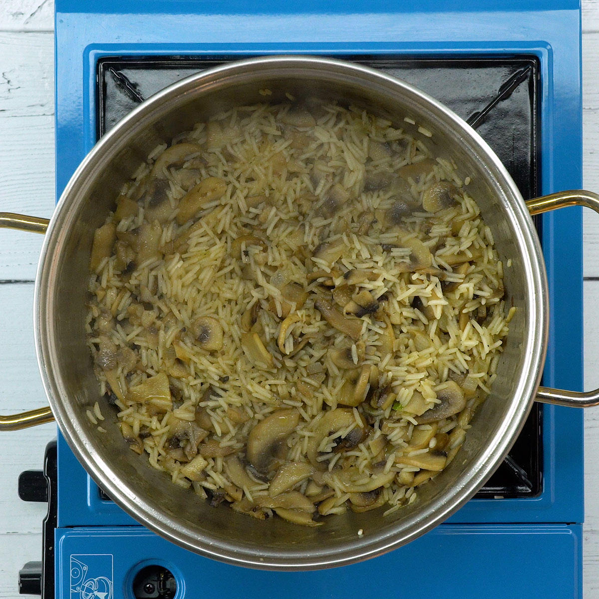 Arroz de cogumelos cozinhando lentamente até secar o líquido.