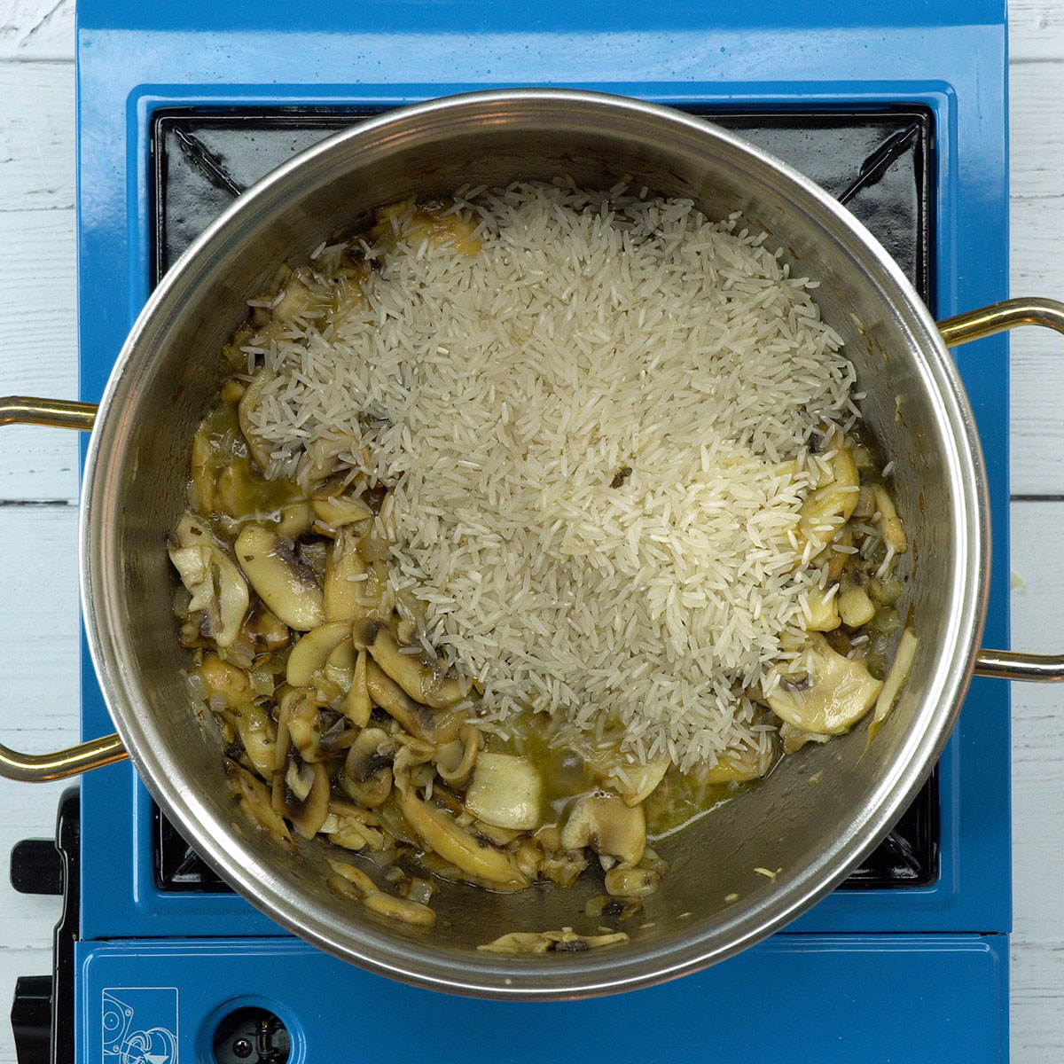 Arroz sendo misturado aos cogumelos e temperos na panela.
