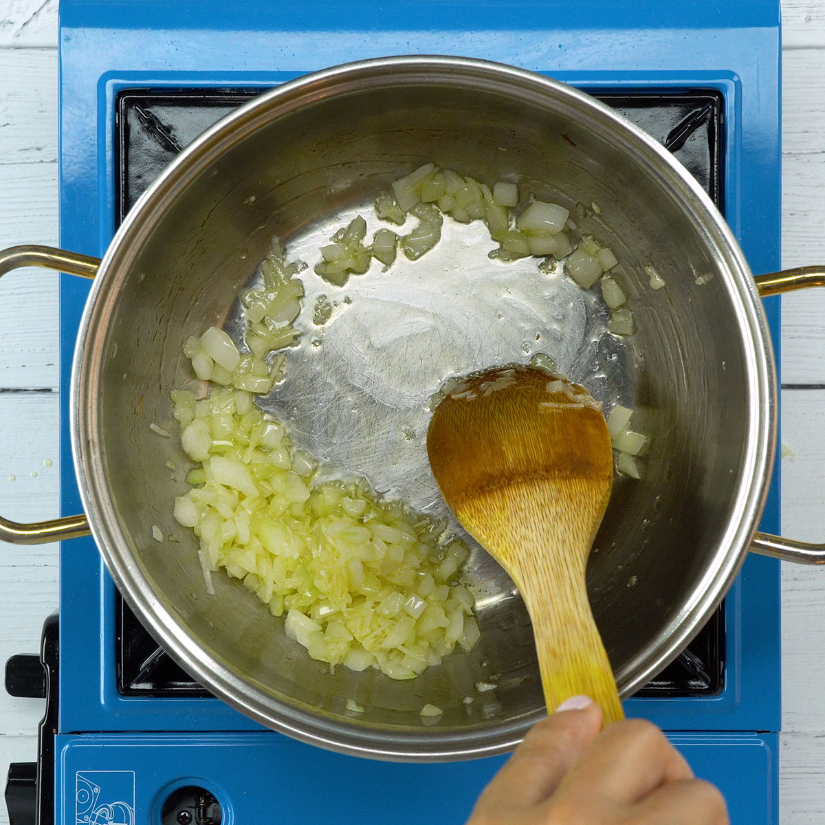 Cebola e alho refogando no azeite para preparar arroz de cogumelos com hambúrguer.