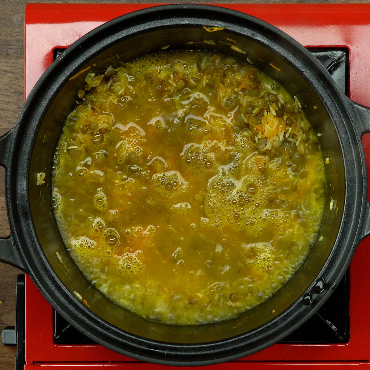 Arroz de lentilhas cozinhando na panela com água fervente até secar.