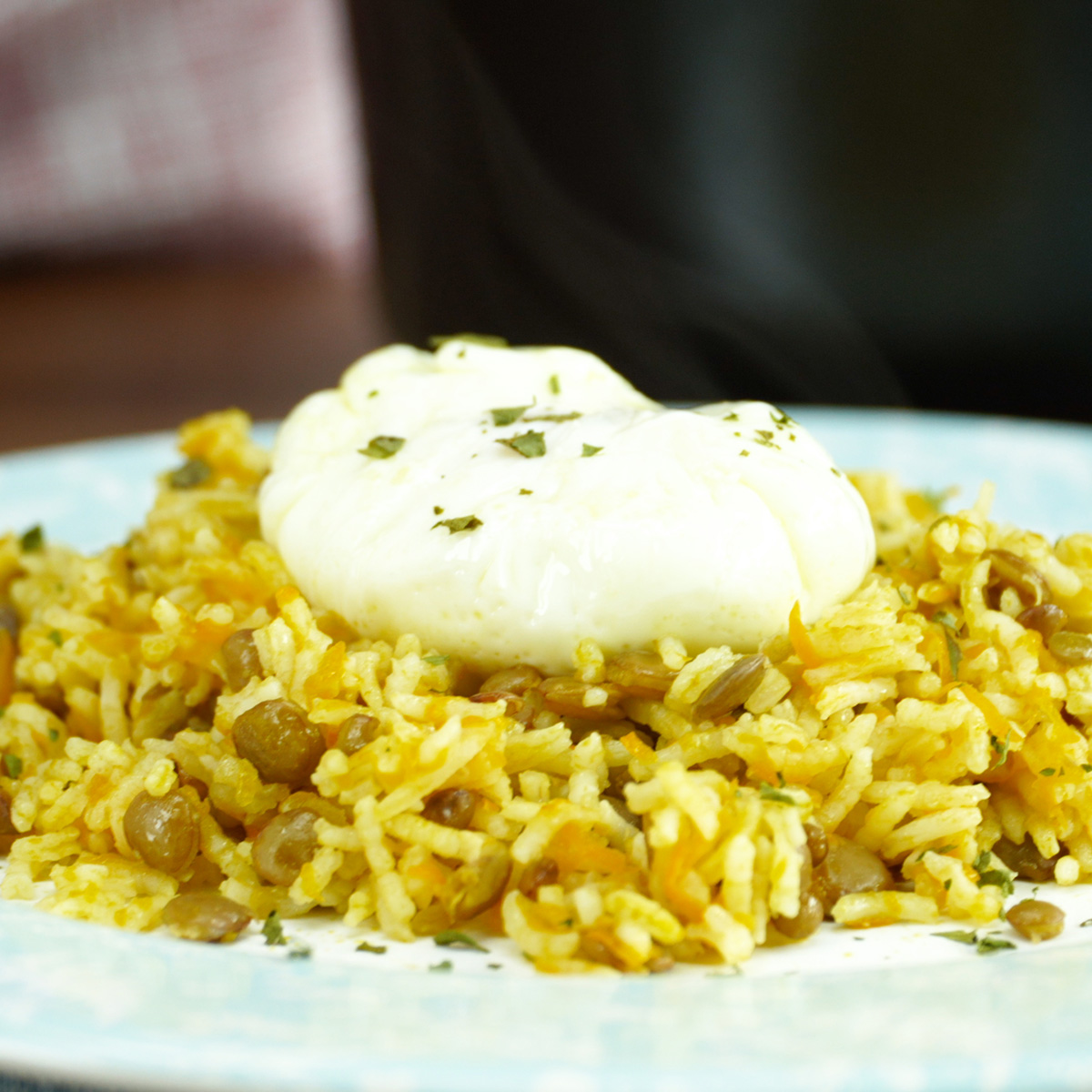 Prato de arroz de lentilhas servido com ovo poché e salsa desidratada.