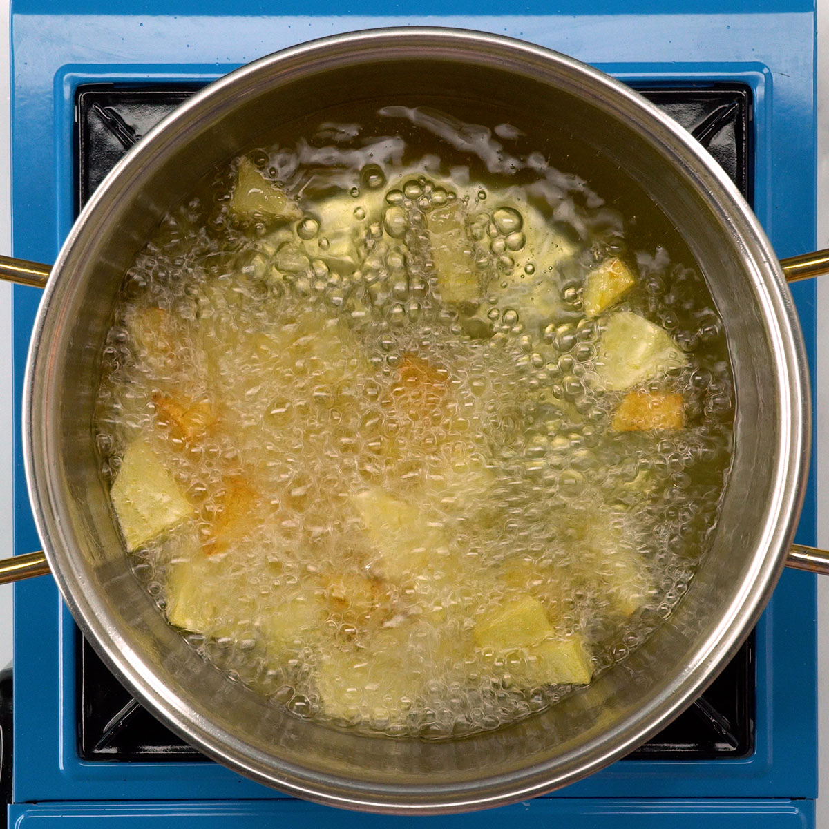 Batatas em cubos fritando até dourar para o bacalhau gratinado com alho-poró.