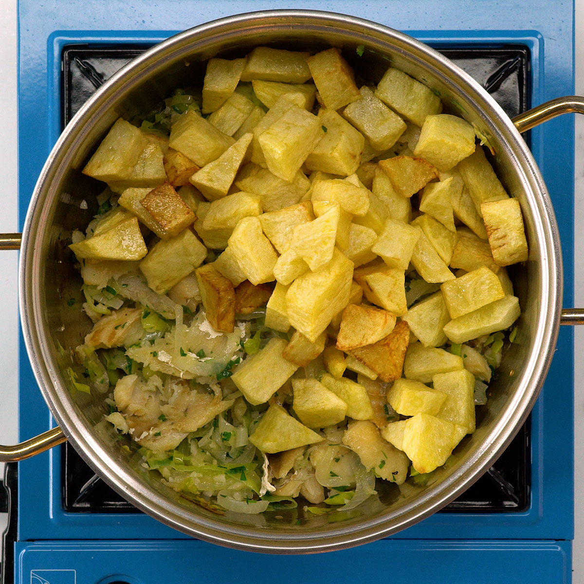 Recheio de bacalhau com batatas e alho-poró sendo misturado.