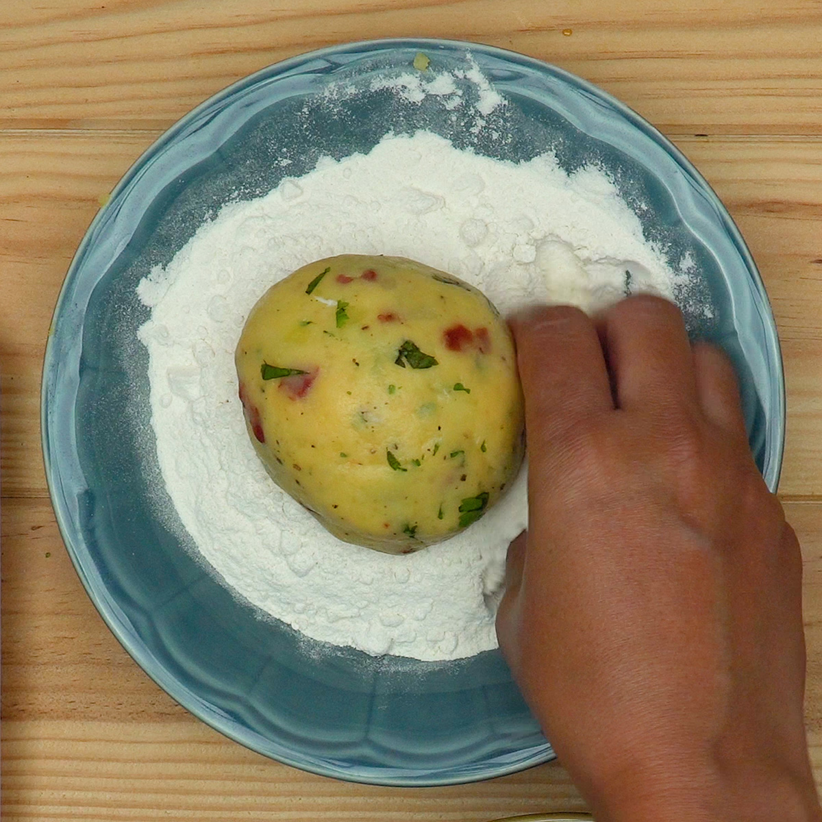 Bolinhos de batata recheados passando pela farinha de trigo.