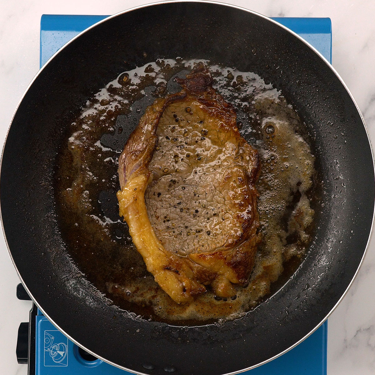 Bife contra filé dourando na frigideira quente com manteiga.
