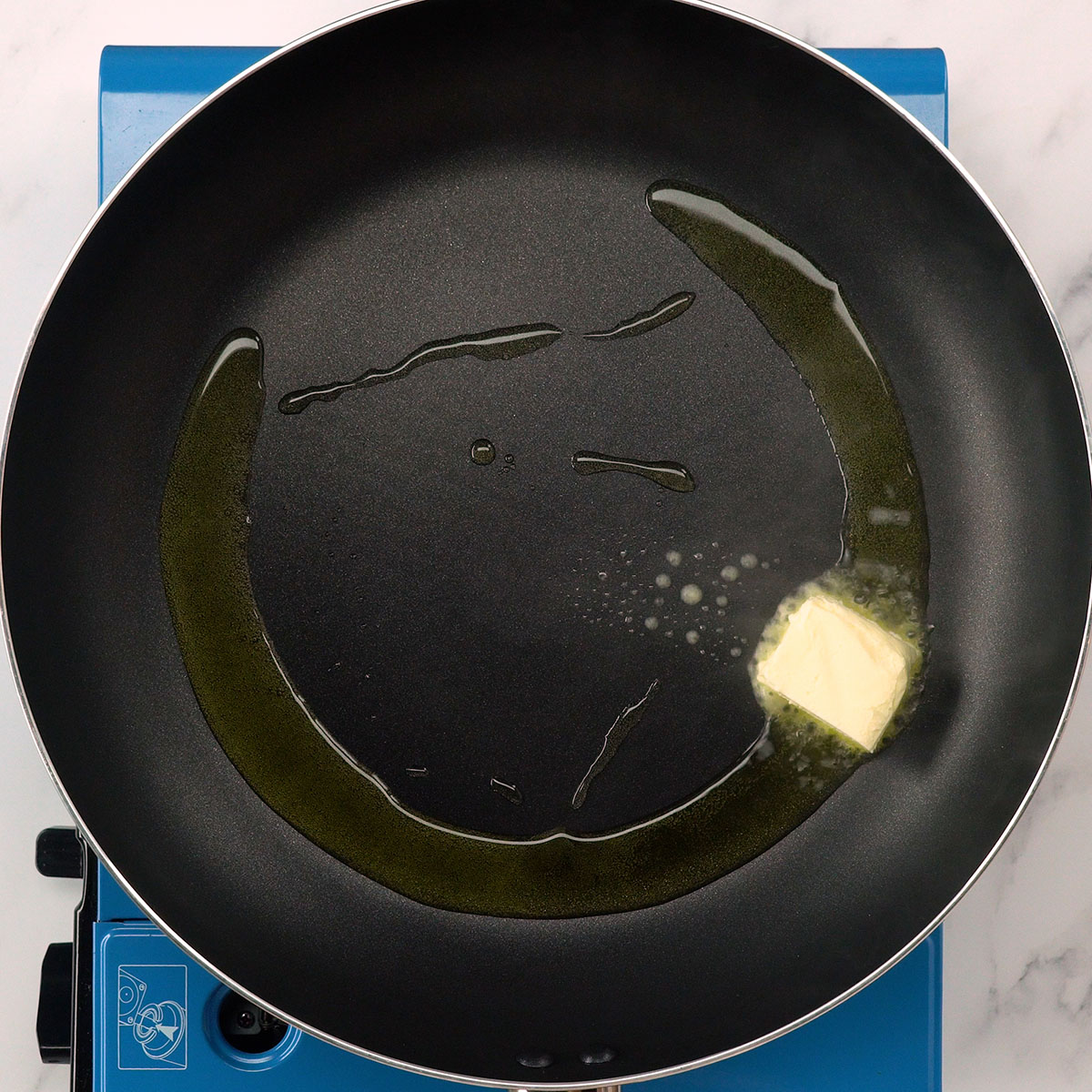 Frigideira aquecendo manteiga e azeite para preparar bife ao molho cremoso.