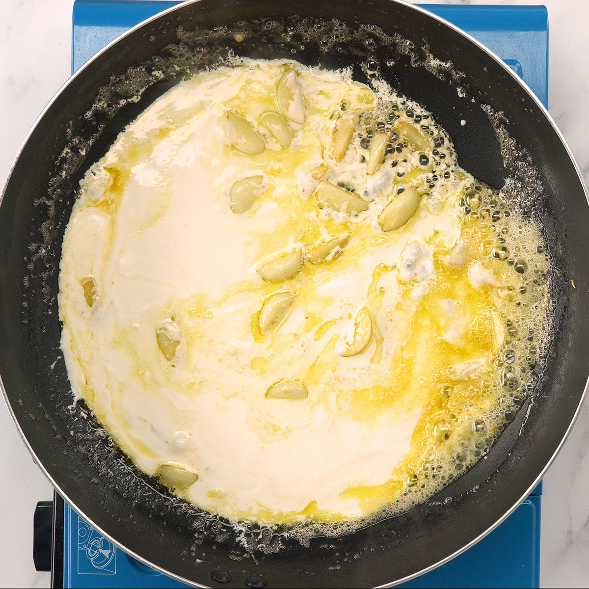 Molho cremoso de alho sendo misturado na frigideira.