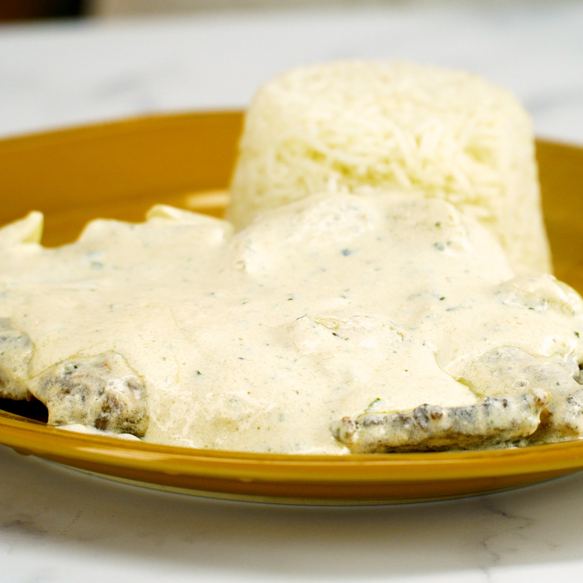 Bife ao molho cremoso de alho servido com acompanhamento caseiro.