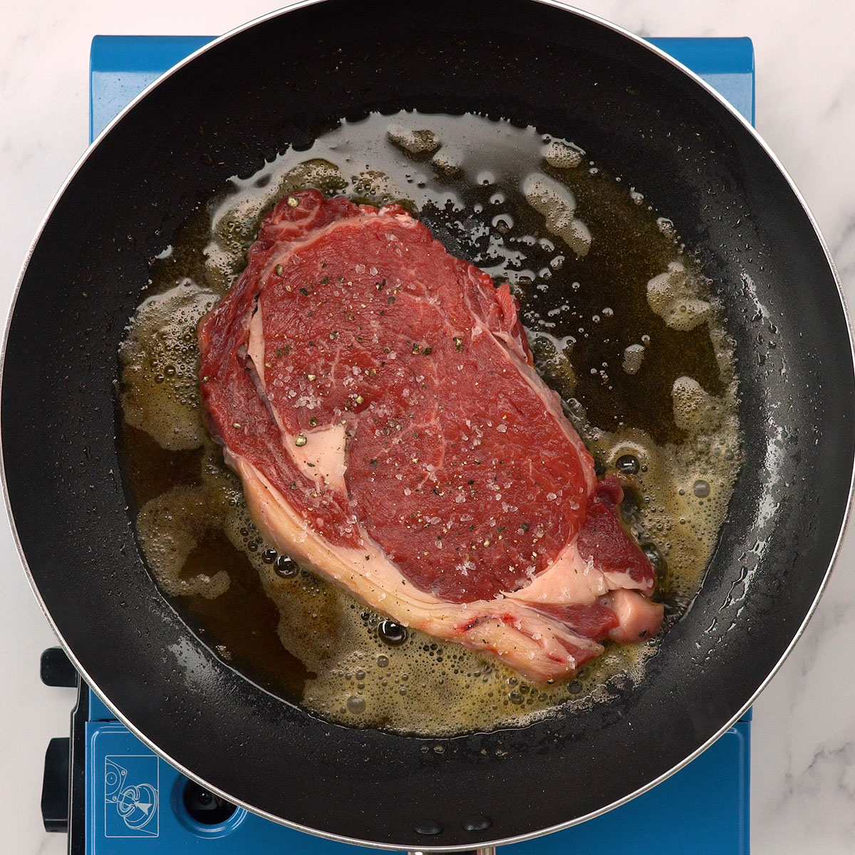Bife sendo temperados com sal e pimenta-do-reino antes da selagem.
