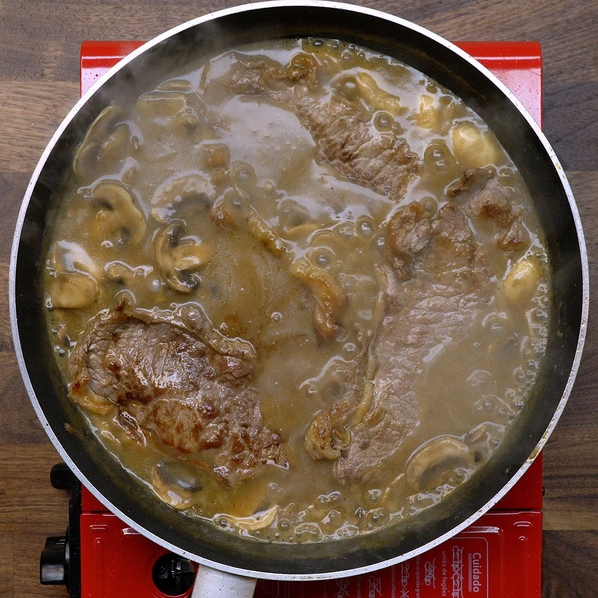 Bifes sendo incorporados ao molho madeira para absorver sabor.